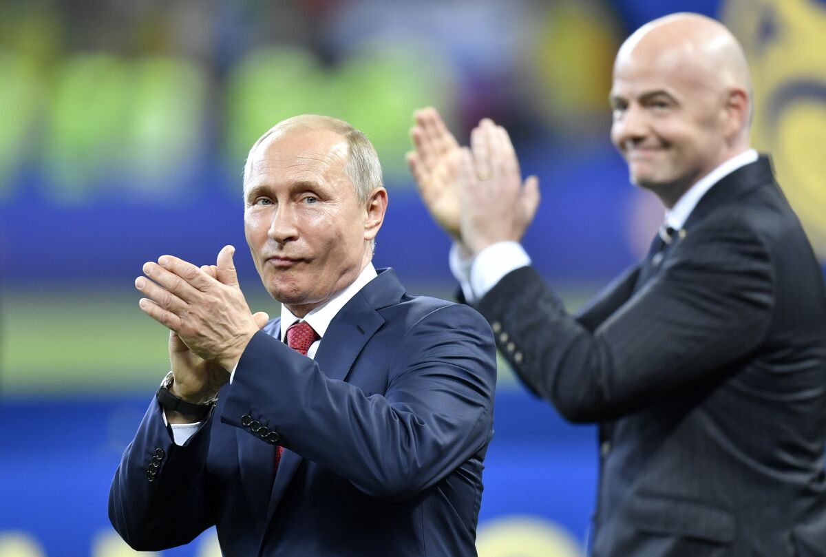 FILE - Russian President Vladimir Putin, left, applauds beside FIFA President Gianni Infantino at the end of the 2018 World Cup final soccer match between France and Croatia in the Luzhniki Stadium in Moscow, Russia, July 15, 2018. FIFA and UEFA have today decided together that all Russian teams, whether national representative teams or club teams, shall be suspended from participation in both FIFA and UEFA competitions until further notice. (AP Photo/Martin Meissner, File)