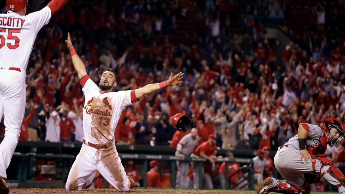 St. Louis' Matt Carpenter (13) celebrates with teammate Stephen Piscotty after scoring past Cincinnati catcher Tucker Barnhart in the ninth inning on Thursday.