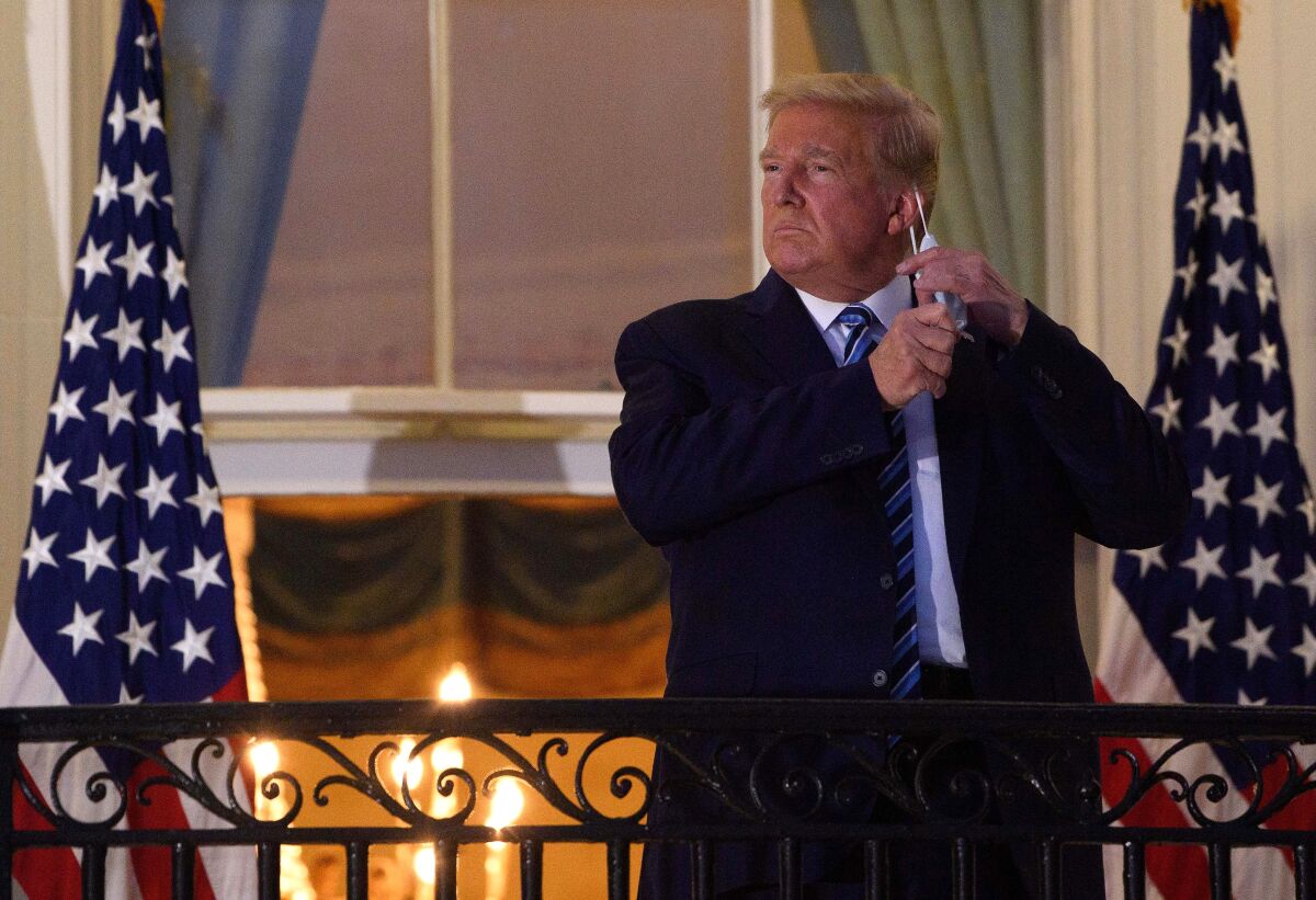 President Trump, stricken with COVID-19, removes his mask after arriving at the White House