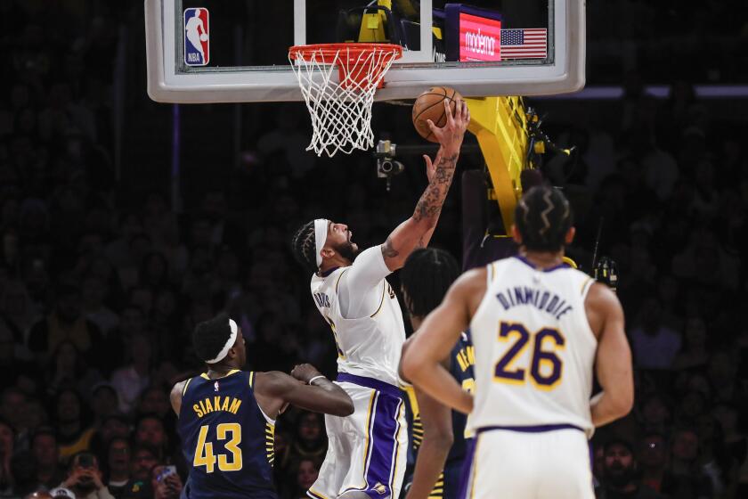Los Angeles Lakers forward-center Anthony Davis, center, scores during the second half of an NBA basketball game against the Indiana Pacers, Sunday, March 24, 2024, in Los Angeles. (AP Photo/Etienne Laurent)