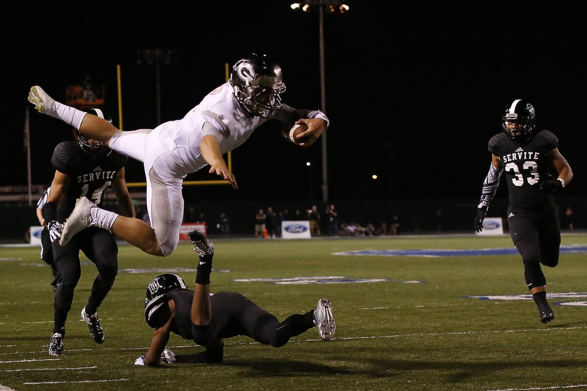 Servite defensive back Maurice Davison dives low as Bishop Gorman quarterback Tate Martell flies over.