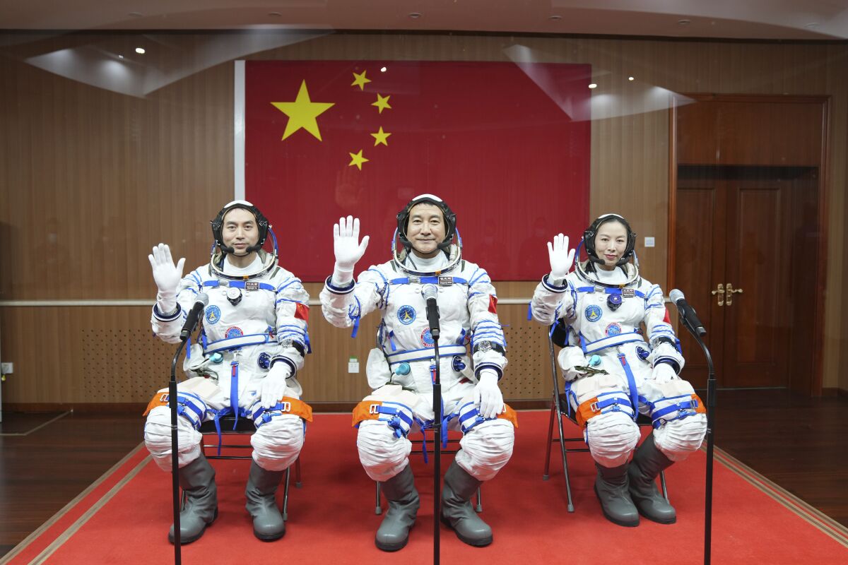 In this photo released by Xinhua News Agency, Chinese astronauts from left, Ye Guangfu, Zhai Zhigang and Wang Yaping wave from behind glass panel before departing for their Shenzhou-13 crewed space mission at the Jiuquan Satellite Launch Center in northwest China, Oct. 15, 2021. Shortly ahead of sending a new three-person crew to its space station, China on Friday renewed its commitment to international cooperation in the peaceful use of space. (Li Gang/Xinhua via AP)