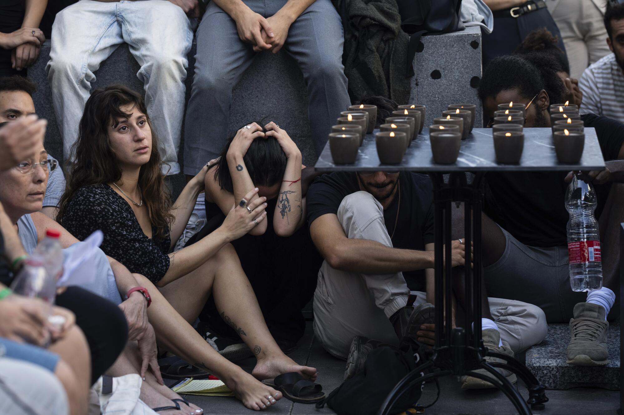 Mourners sit near a table with lighted candles at a funeral of an Israeli man killed by Hamas militants.