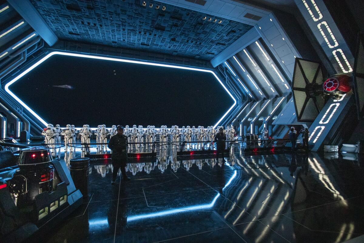 A member of the First Order and 50 Stormtroopers stand guard next to a TIE fighter in the hangar bay of the First Order Star Destroyer during a media preview Thursday.