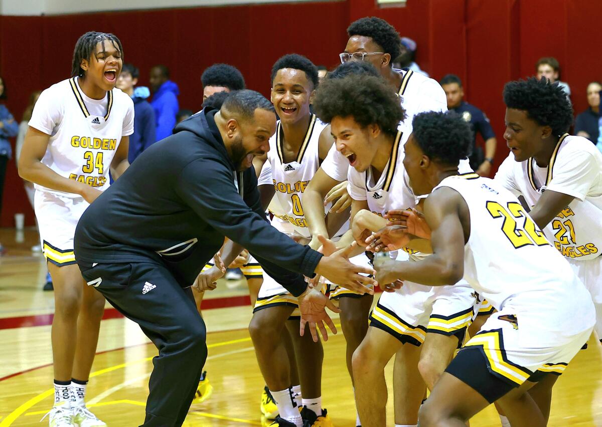King/Drew coach Lloyd Webster celebrates with his players after winning the City Section Open Division championship.