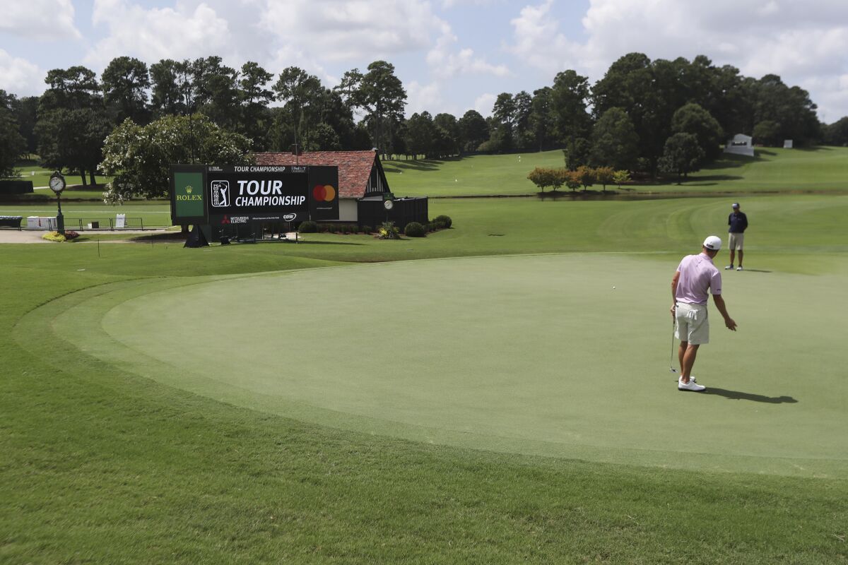 Justin Thomas and his instructor are the only ones around to react to his putt on the 18th green during his practice round for the season-ending Tour Championship at East Lake Golf Club on Wednesday, Sept. 2, 2020, in Atlanta. (Curtis Compton/Atlanta Journal-Constitution via AP)