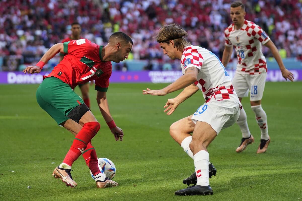 El croata Borna Sosa (centro) y el marroquí Hakim Ziyech disputan el balón 