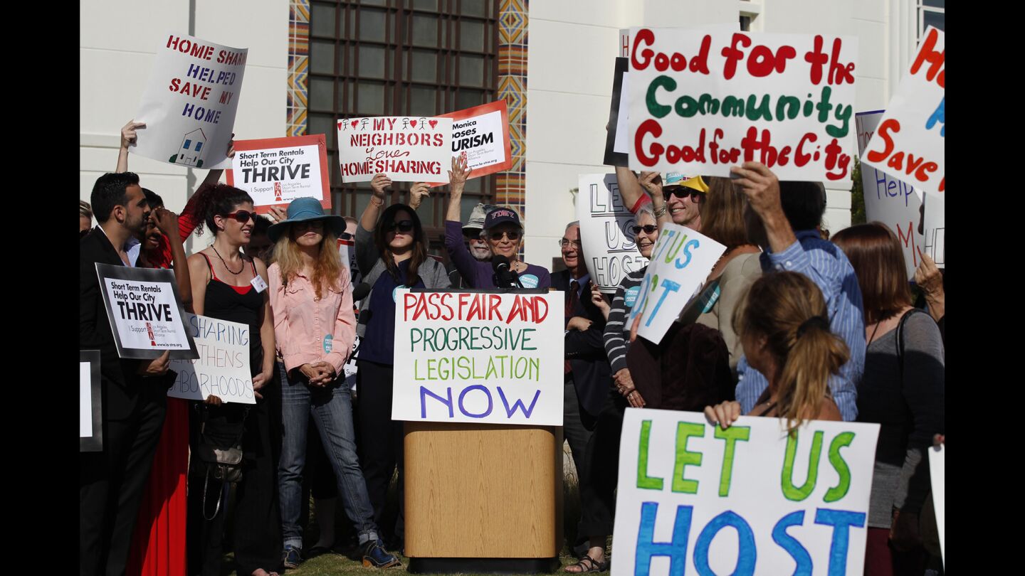 Airbnb supporters listen to Airbnb host Arlene Rosenblatt speak during a rally outside the Santa Monica City Council as they are set for a second and final vote on regulations that would outlaw most short-term rentals in the beach city.