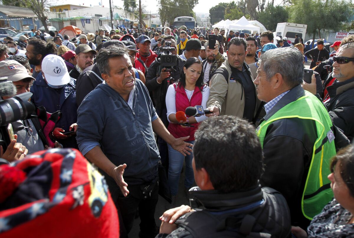 Irineo Mújica, líder de Pueblo Sin Fronteras, tiene una discusión con Sergio Tamai, a la derecha, que es el jefe de Angels Without Borders, mientras se encuentra frente al complejo deportivo Benito Juárez en Tijuana el sábado.