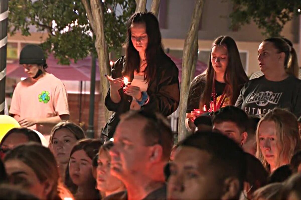 Hundreds gather for a candlelight vigil outside the Corona movie theater where two people were shot July 26.