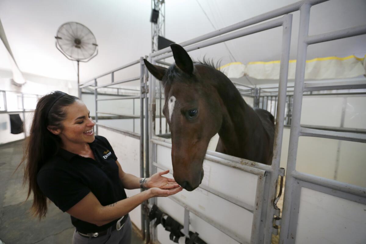 Rebecca Ratte, a rider and aerialist, interacts with a horse before practice for the "Odysseo" by Cavalia show in Irvine.