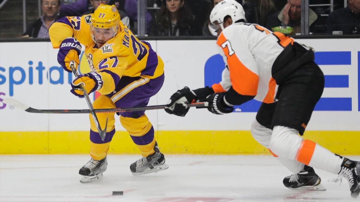 Kings defenseman Alec Martinez moves the puck under pressure from the Flyers forward Wayne Simmonds during the first period of a game on Oct. 14.