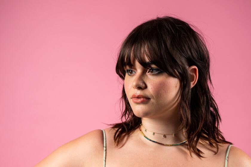 Barbie Ferreira of "Euphoria" posing with hand to hip, bangs in a green flowered dress 