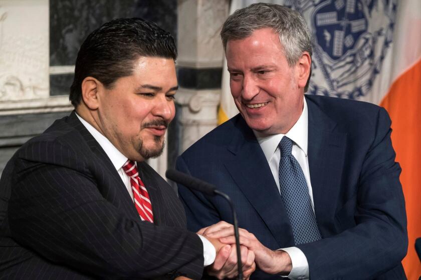 In this photo provided by the Mayoral Photography Office, Richard A. Carranza, left, is introduced by New York Mayor Bill de Blasio, right, as his new choice to lead the nation's largest school system Monday, March 5, 2018, at City Hall in New York. Carranza, who has been the superintendent in Houston since August 2016 and previously was superintendent of the San Francisco school system, has been appointed to replace Chancellor Carmen Farina, who's retiring. (Ed Reed/Mayoral Photography Office via AP)