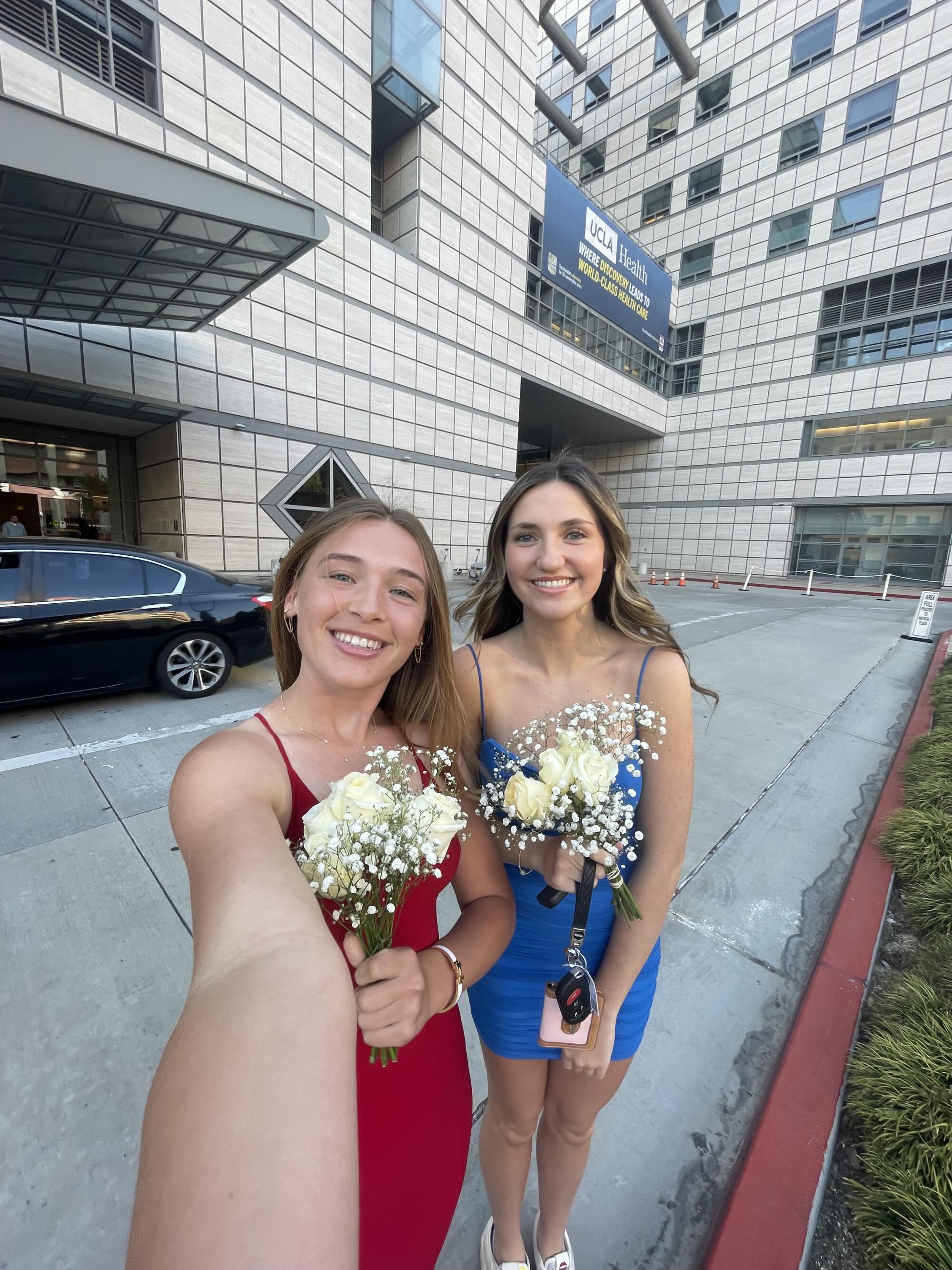 Mackenzie McGovern and Kate Henson stand outside Ronald Reagan Medical Center in their prom dresses.