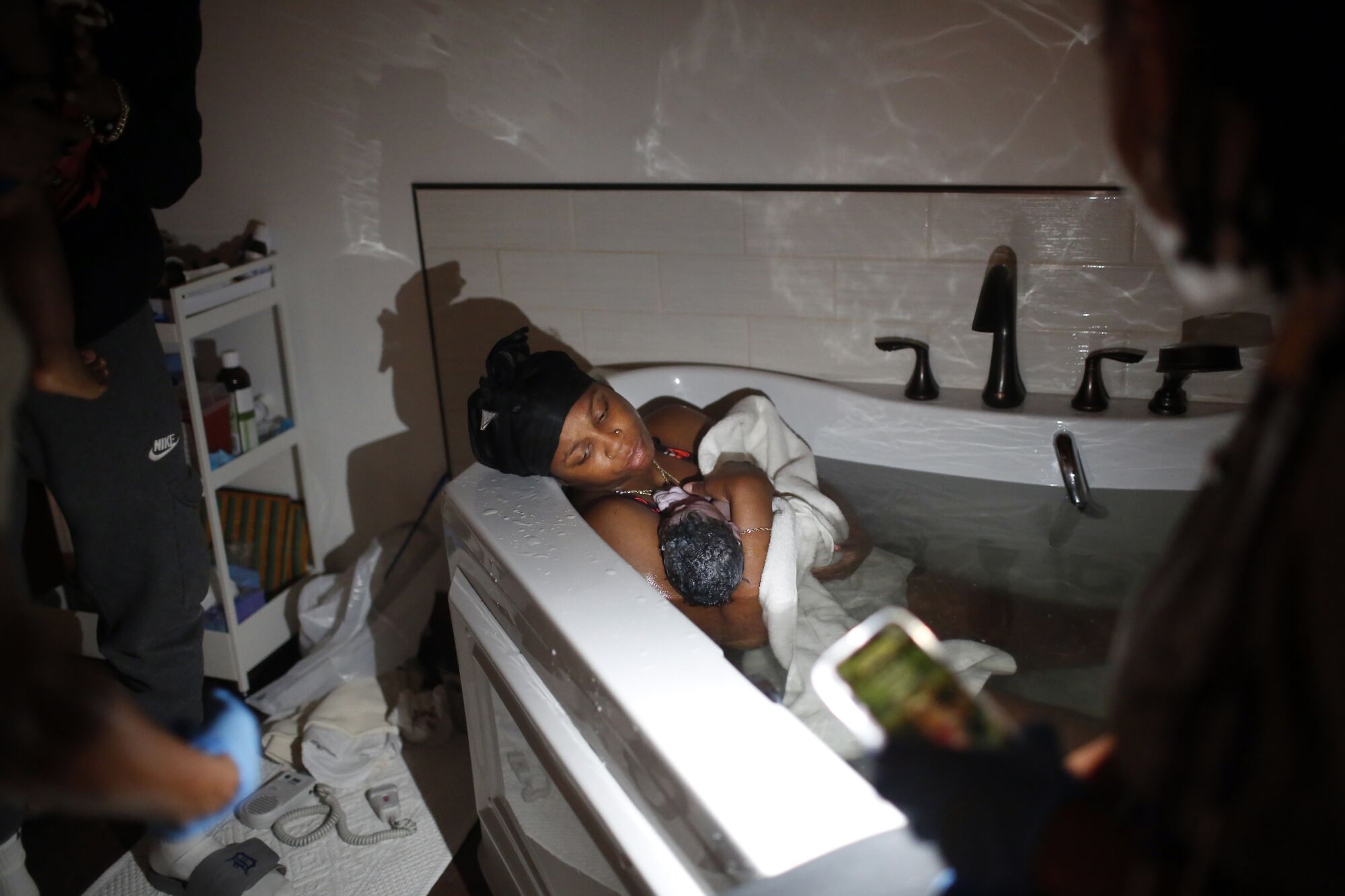 A mother holds her newborn in a tub