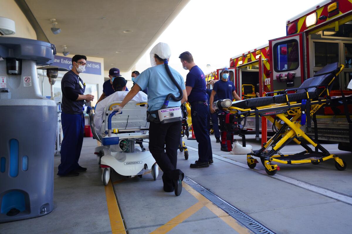 A patient on a stretcher is wheeled from an ambulance into a hospital