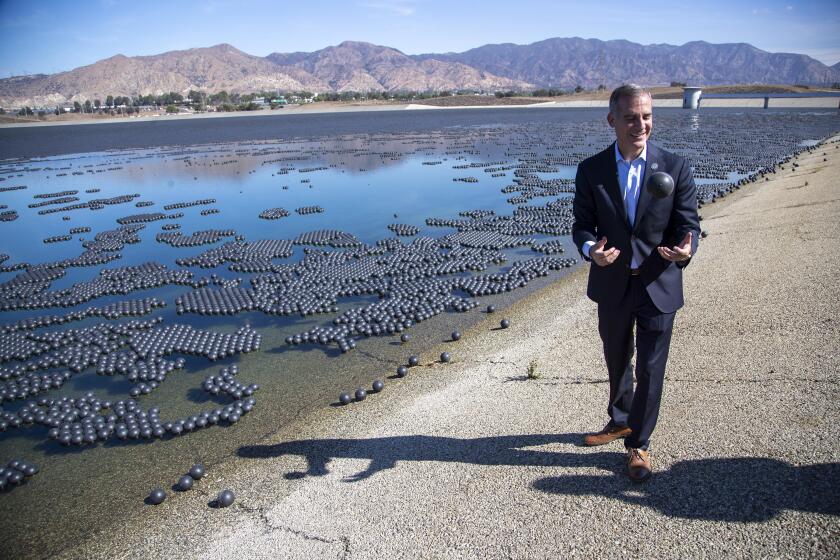 GRANADA HILLS, CA - October 05 2021: Mayor Eric Garcetti tosses one of thousands of black plastic balls used to help with evaporation at the Los Angeles Reservoir following a press conference on Tuesday, Oct. 5, 2021 in Granada Hills, CA. (Brian van der Brug / Los Angeles Times)