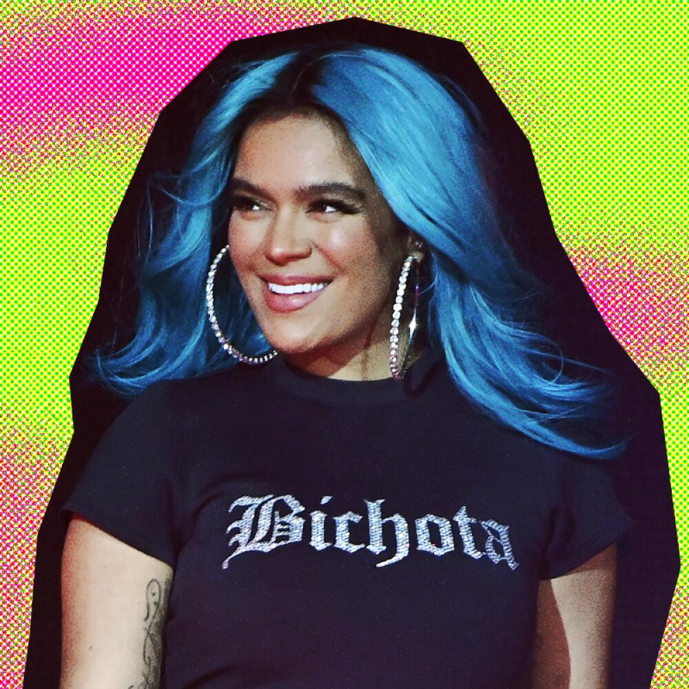 A woman with blue hair and hoop earrings wears a black, cropped shirt reading "Bichota."