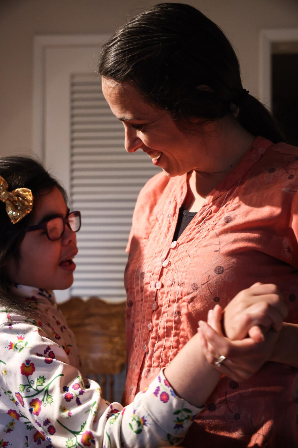 A girl smiles as she dances with her mother.