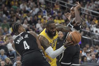 Los Angeles Lakers forward LeBron James, center, drives between Brooklyn Nets guards Dennis Smith Jr. (4) and Lonnie Walker IV, right, during the first half of a preseason NBA basketball game Monday, Oct. 9, 2023, in Las Vegas. (AP Photo/Sam Morris)