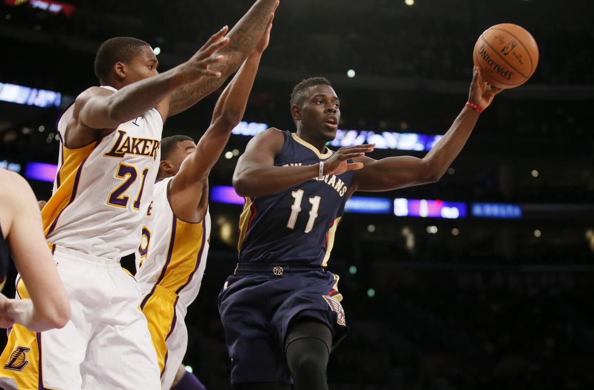 Pelicans point guard Jrue Holiday (11) is forced to pass after driving down the lane against Lakers forward Ed Davis (21) and point guard Ronnie Price in the first half.