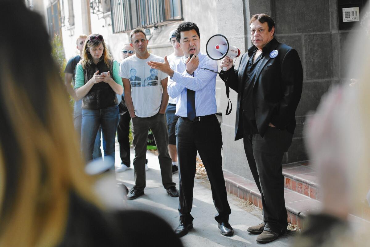 Then-L.A. City Council candidate David Ryu speaks in April at a rally organized by Larry Gross, right, with the Coalition For Economic Survival, for residents of the Villa Carlotta apartment building on Franklin Avenue in Hollywood. Ryu pledged to oppose turning the building beloved by tenants into a hotel.