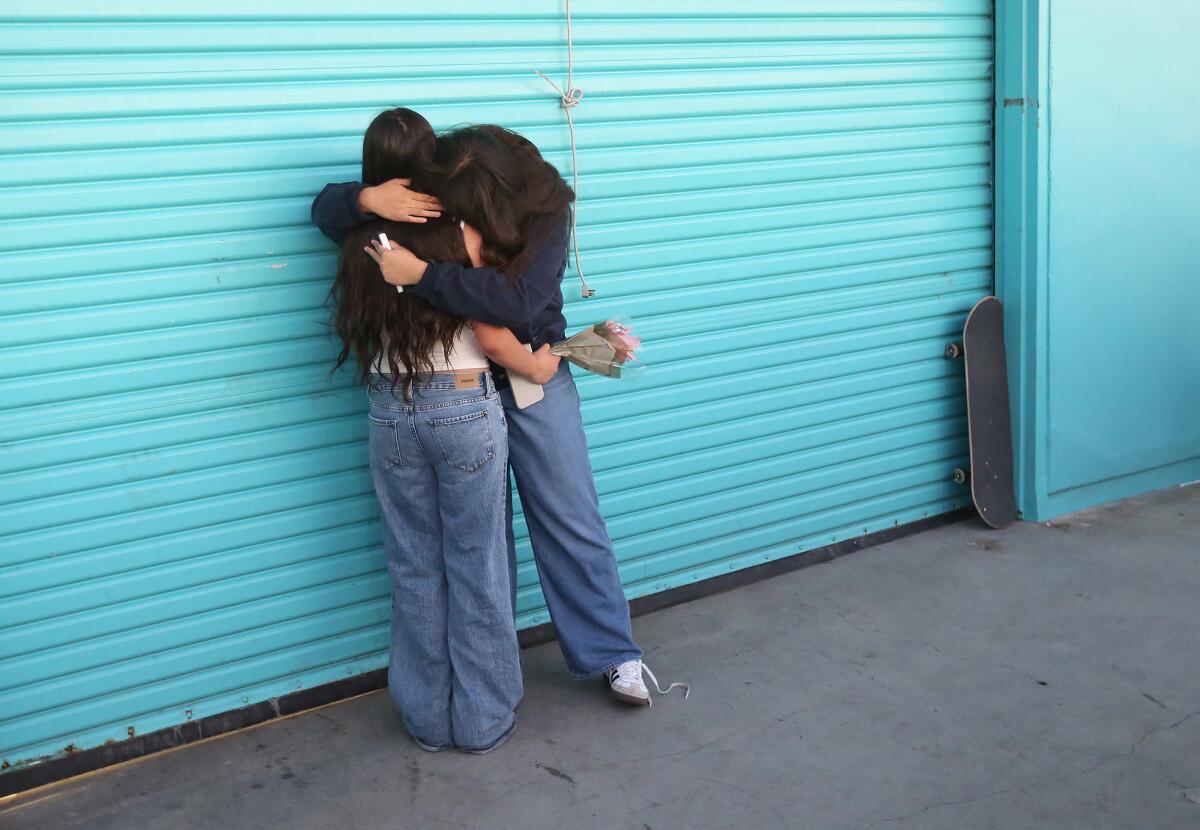 Two friends hug as they gather at the end of the pier to throw flowers and remember 15-year-old Aayan Randhawa.