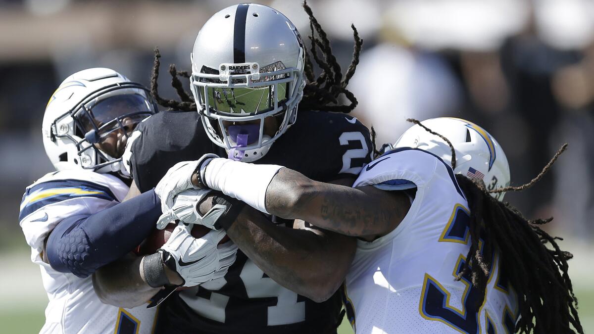 Raiders running back Marshawn Lynch is tackled by the Chargers' Adrian Phillips, left, and Tre Boston during the first half of their game Oct. 15.