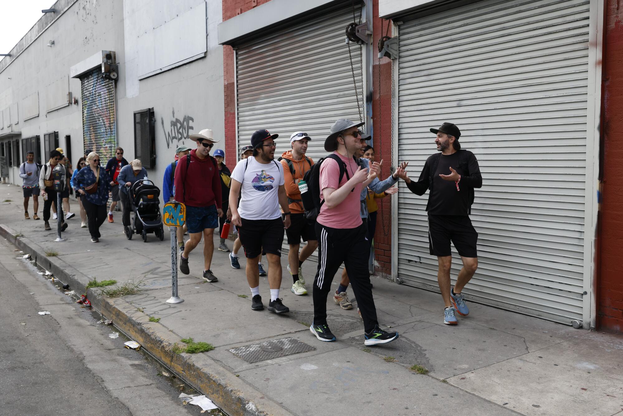 A group of walkers pass by closed storefronts.