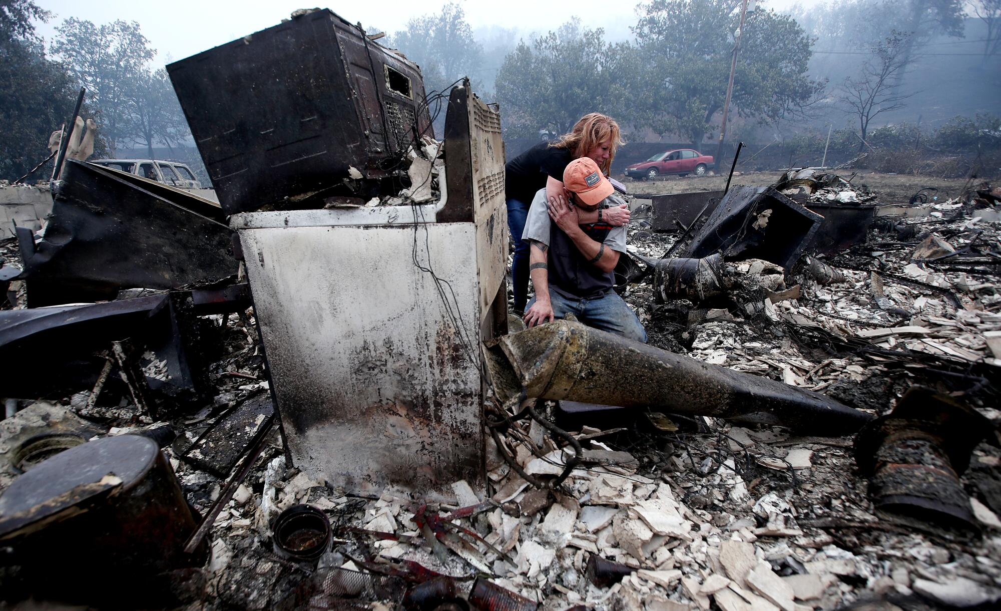 Sheri Marchetti-Perrault and James Benton embrace as they sift through the remains of their home near Yreka, Calif.