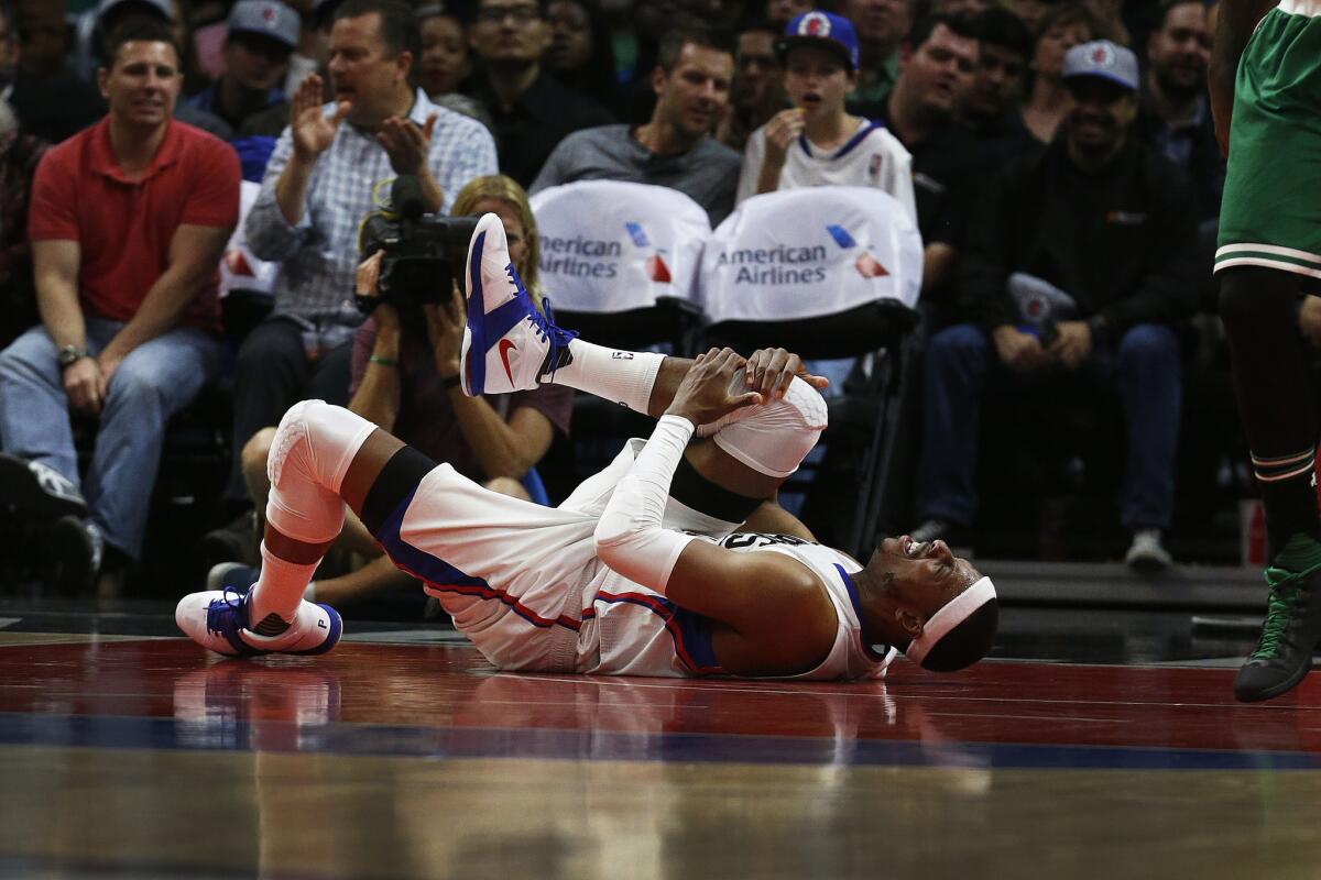 Clippers forward Paul Pierce holds his leg in pain after coming down from a shot during the second half of a game against the Celtics.