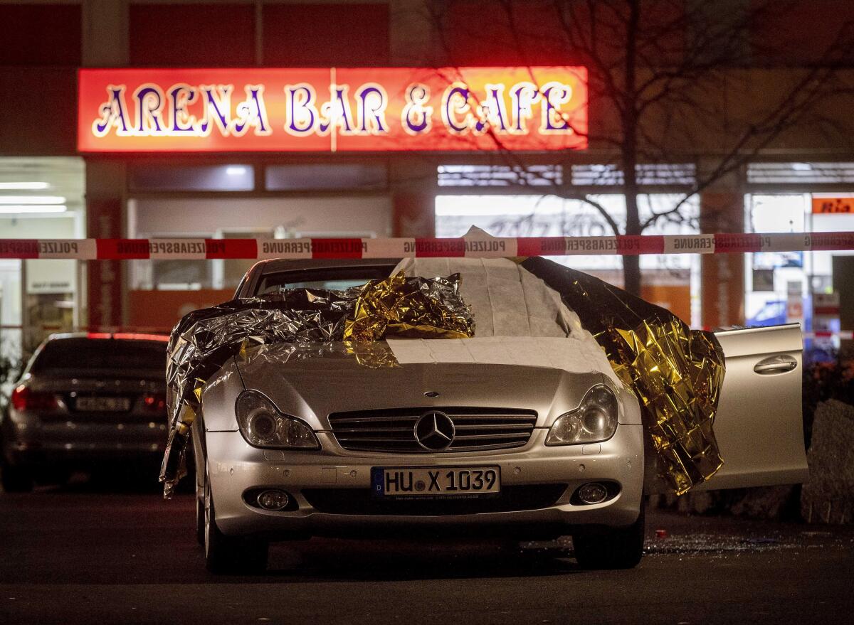 Thermal blankets cover a car in Hanau, Germany, near the scene of a shooting Wednesday.