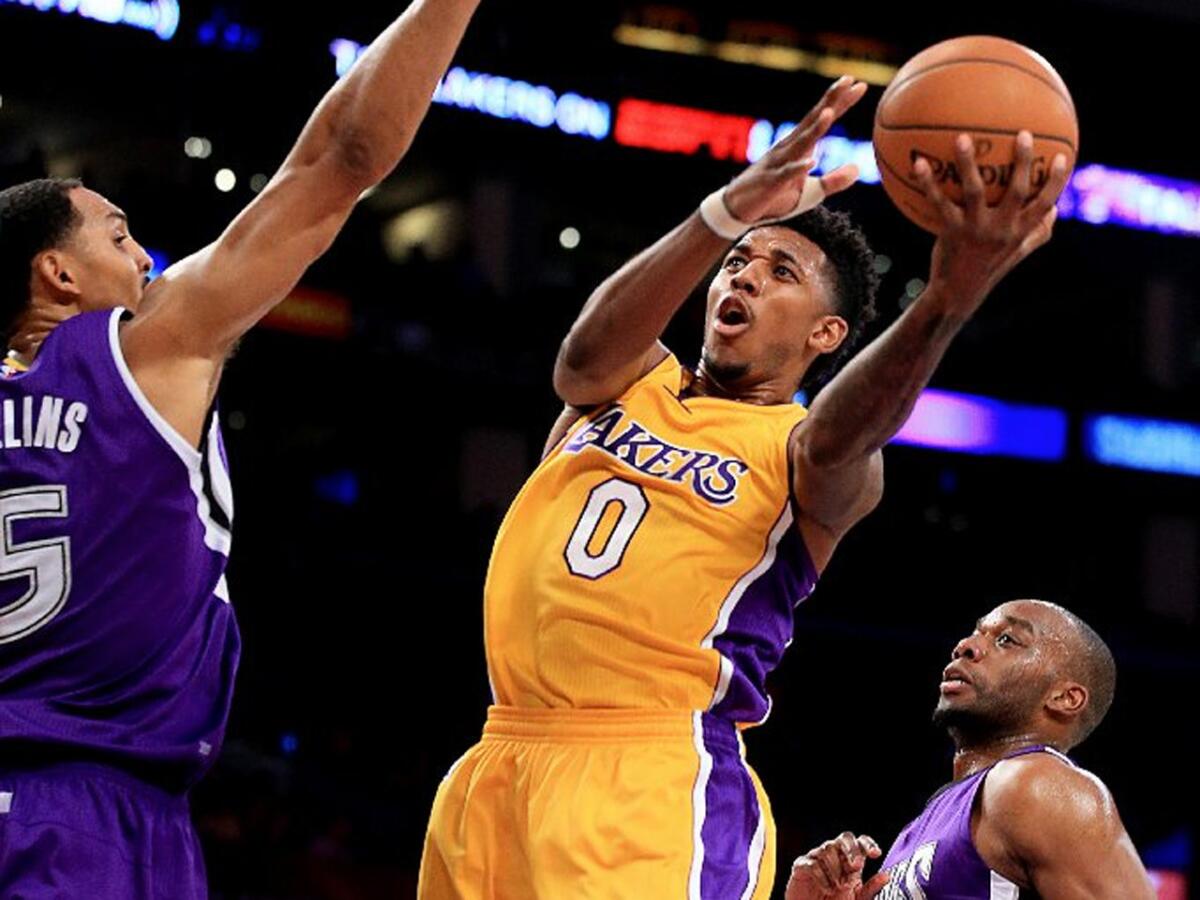 Lakers swingman Nick Young splits the defense of Kings Ryan Hollins, left, and Carl Landry in the second quarter. Young finished with 12 points.