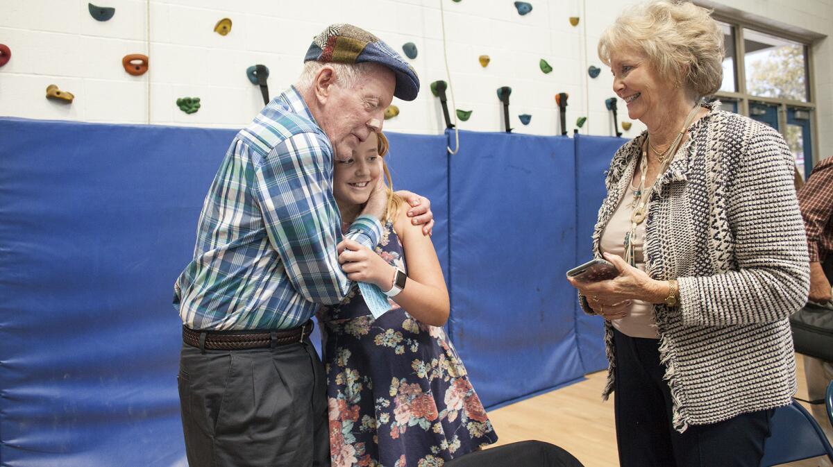 Sixth-grader Charlotte Riches gets a hug from her grandfather John Hall as grandmother Cari Hall looks on after Charlotte shared her interview of him during an oral history luncheon at Thurston Middle School in Laguna Beach.