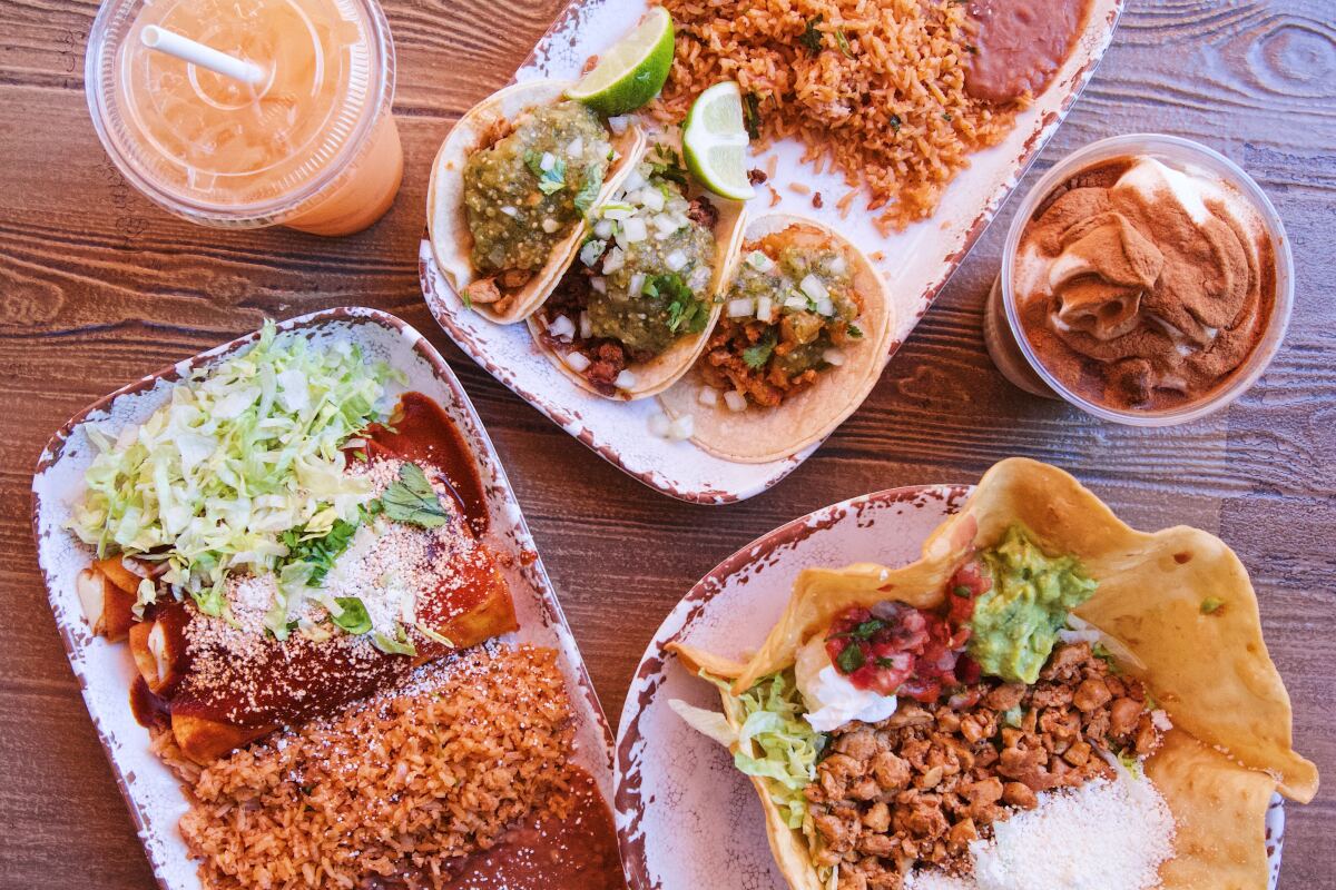 An overhead photo of a table of street tacos, enchiladas, horchata with cold brew, melon agua fresca and a taco salad