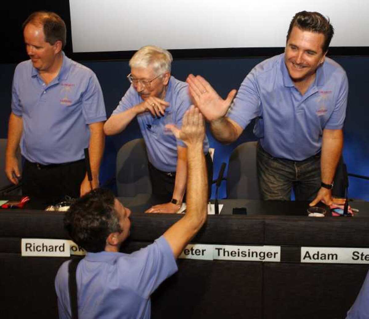 Adam Steltzner, at right, the Mars Science Laboratory entry, descent and landing phase lead, gives a high five to one of the engineers who were part of the mission at JPL at the post-landing press conference.