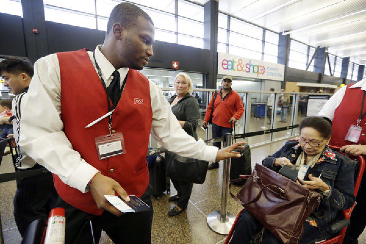 Wheelchair attendant Erick Conley, left, assists an elderly passenger heading overseas at Seattle-Tacoma International Airport in SeaTac, Wash. Voters will decide on whether to raise the city's minimum wage to $15 an hour.