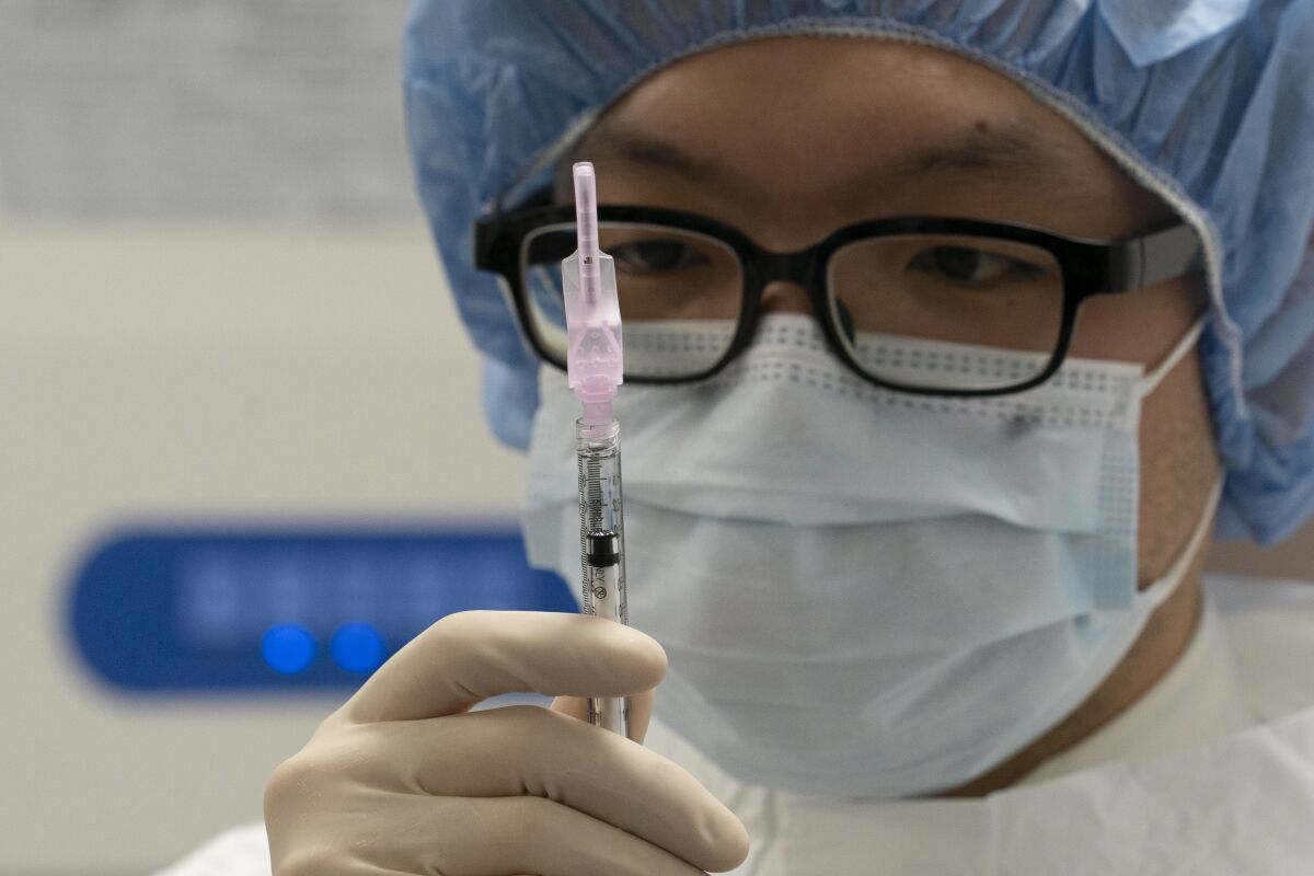 A pharmacist holds a syringe in a room where COVID-19 vaccine will be prepared 