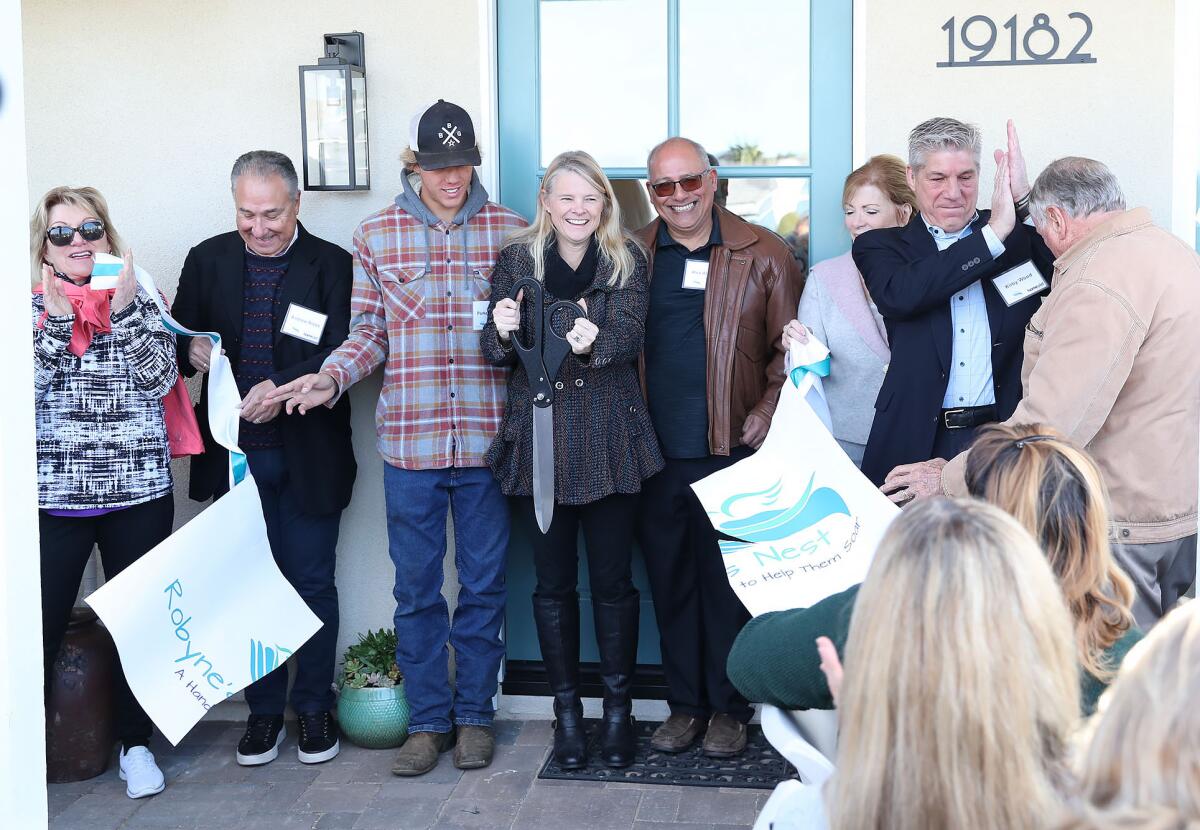 Robyne Wood cuts the ribbon at the Robyne's Landing student transitional living home.