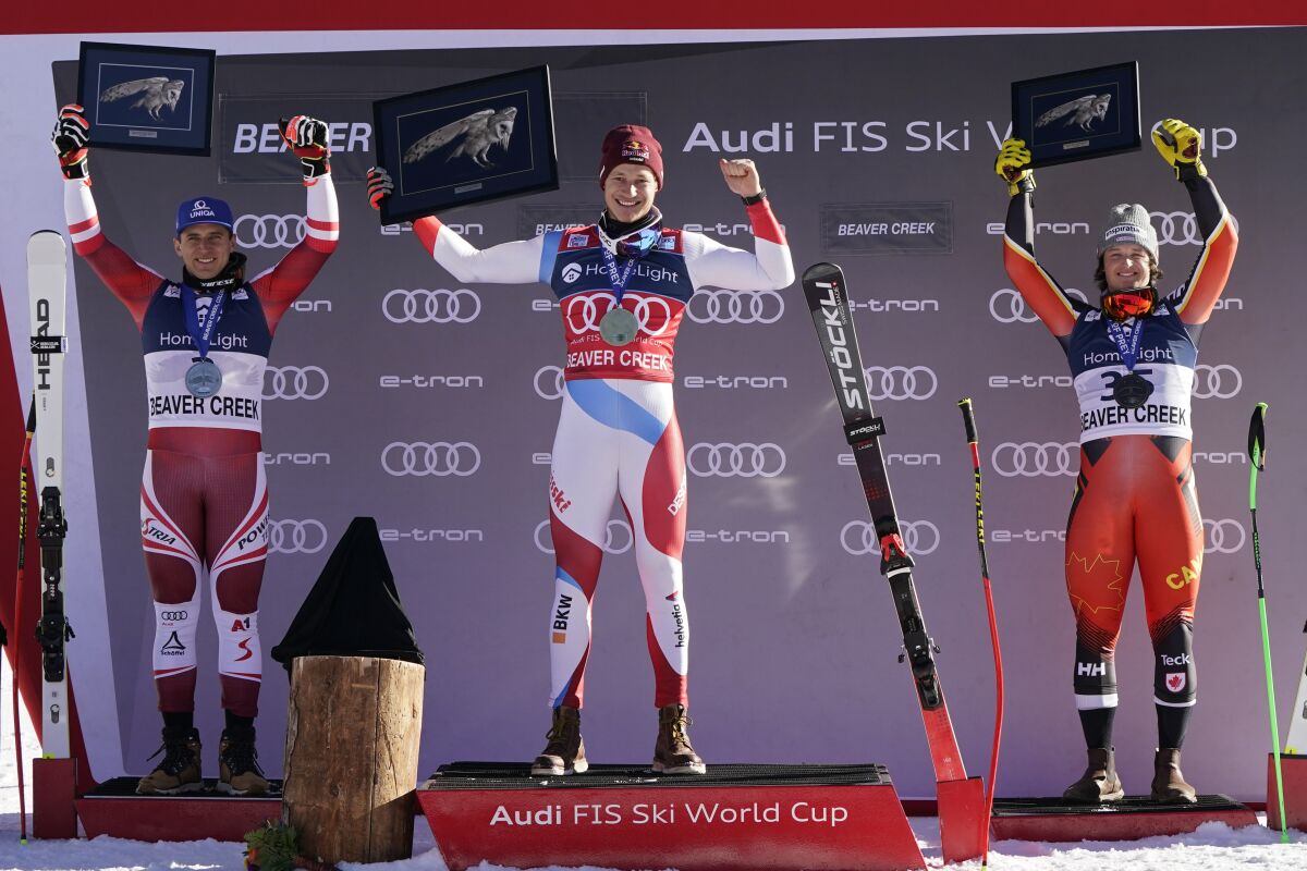 First-place finisher Switzerland's Marco Odermatt, center, celebrates while posing on the podium beside second-place finisher Austria's Matthias Mayer, left, and third-place finisher Canada's Broderick Thompson after a men's World Cup super-G skiing race Thursday, Dec. 2, 2021, in Beaver Creek, Colo. (AP Photo/Gregory Bull)
