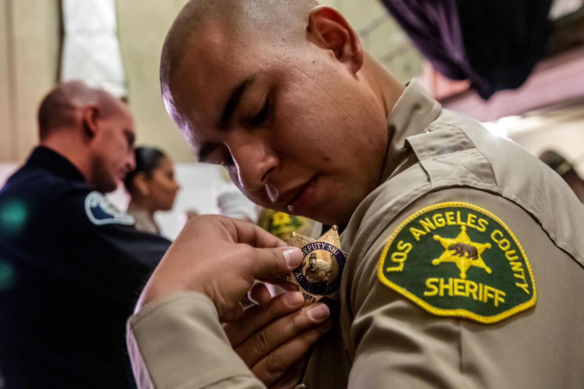 Los Angeles County Sheriff Academy Class 464 graduate Oscar Mora puts badge on his uniform at graduation