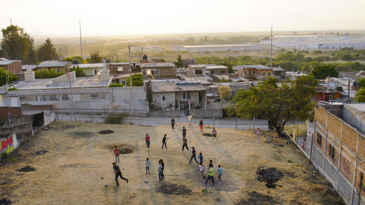 Residents of Lo de Juarez, a small community in Mexico's Guanajuato state, play soccer. In the background is a Ford plant, one of the nearby auto factories that have transformed the town's labor force.