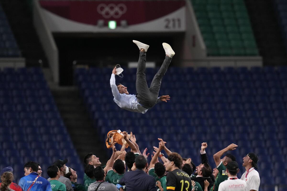 Mexico players toss coach Jaime Lozano into the air following the team's bronze-medal win over Japan in the Tokyo Olympics.