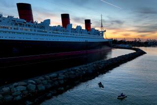 Long Beach, CA - February 17: Amid cool weather, people fish from a kayaks with a view of the historic RMS Queen Mary ocean liner, that is 1,019.4 feet long and 181 feet high at dusk Friday, Feb. 17, 2023 in Long Beach. The RMS Queen Mary was first put in service from 1936 and retired in 1967 as a ship museum and hotel, and is currently being refurbished. (Allen J. Schaben / Los Angeles Times)