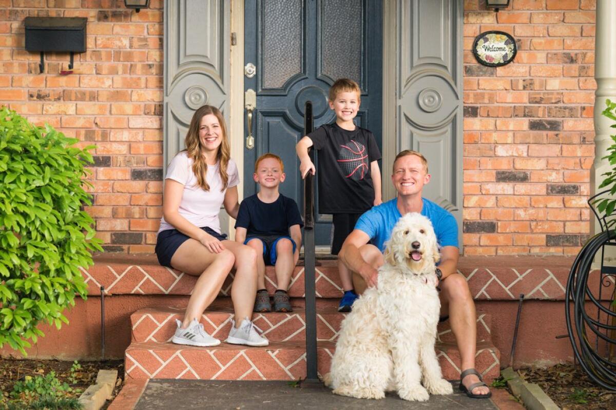 Shawn Ashmore and his family, dog included, sit on the steps outside their home.