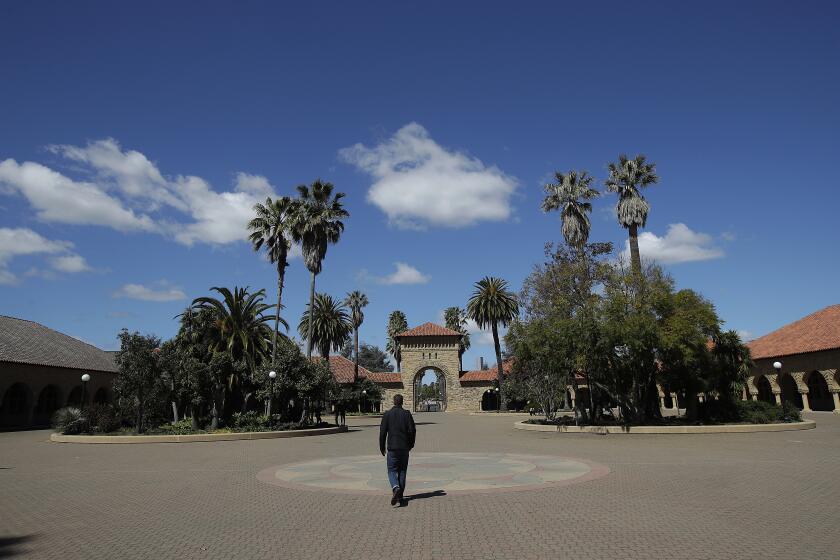 In this April 9, 2019 photo, a pedestrian walks on the campus at Stanford University in Stanford, Calif. (AP Photo/Jeff Chiu)