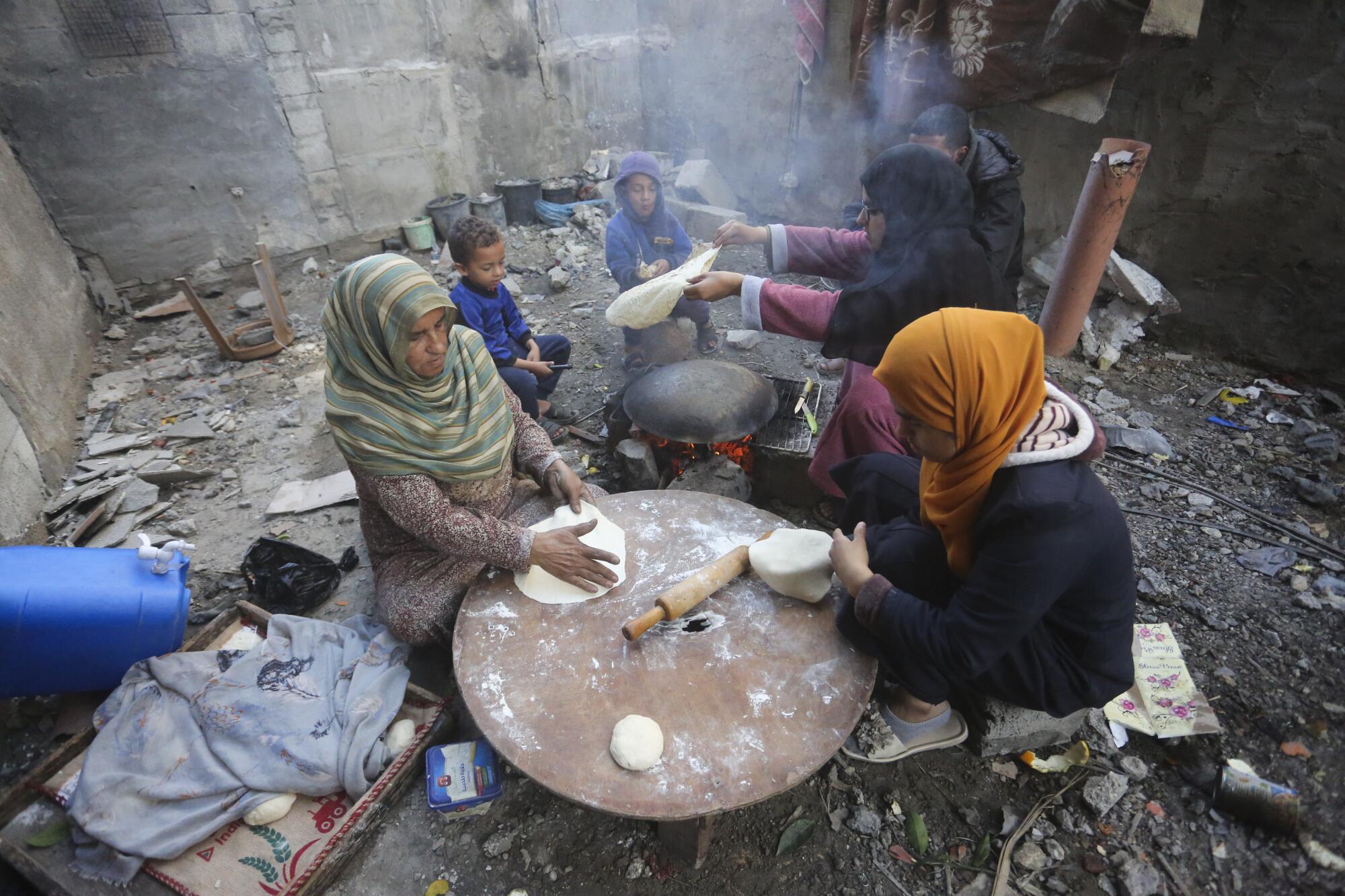Women baking bread by their destroyed homes in Gaza