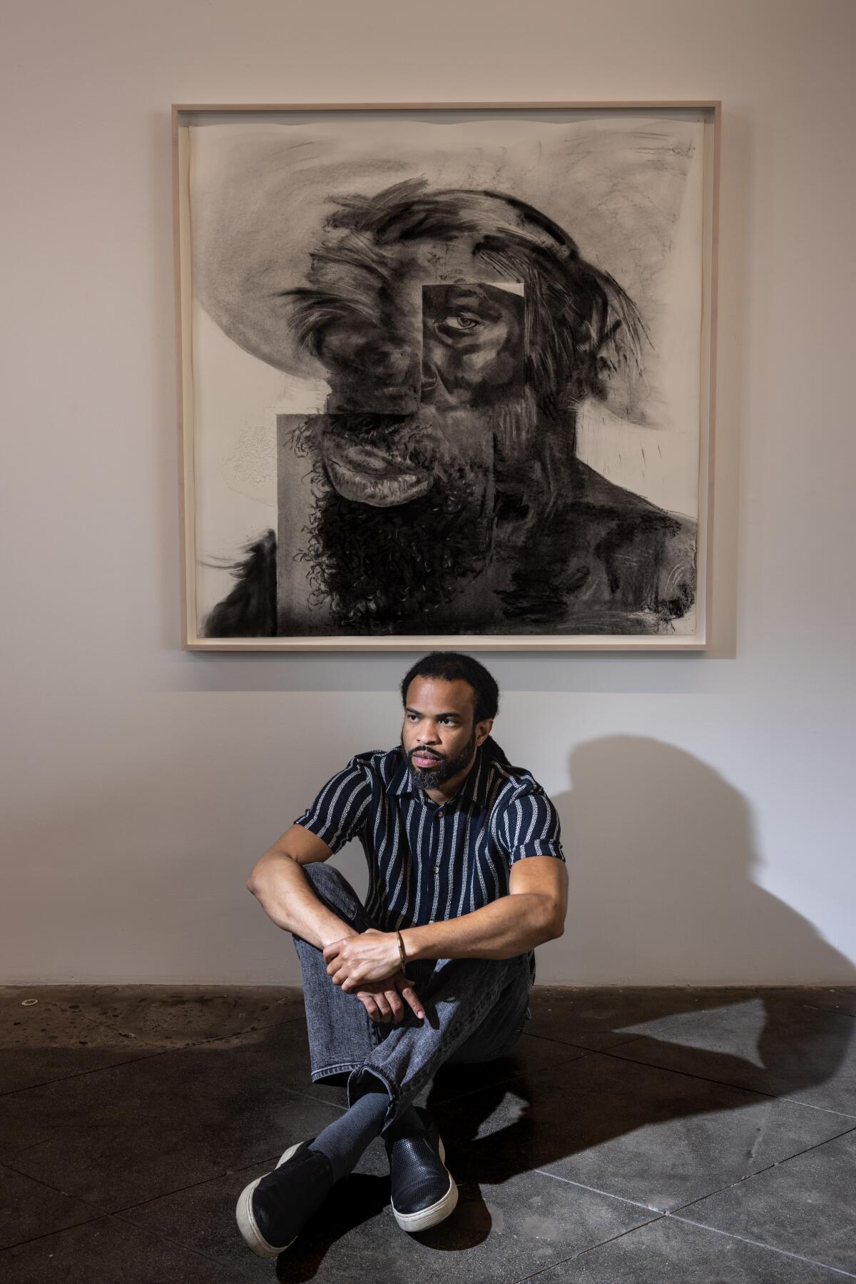 Cosmo Whyte sits in front of one of his artworks.