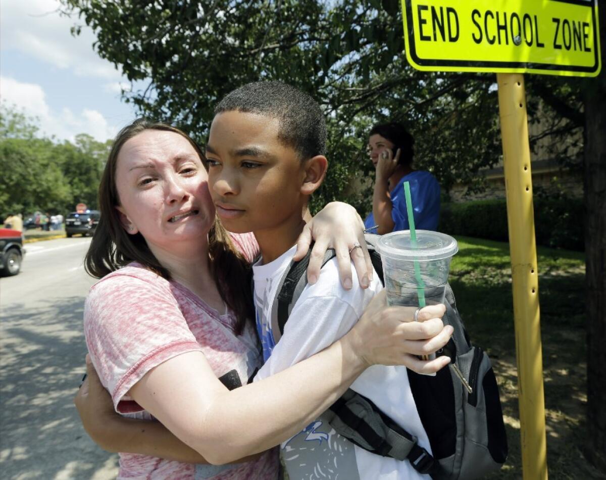 Lora Ross, left, hugs her son Jonathan Ross, 14, outside Spring High School in Spring, Texas. Students were dismissed after a 17-year-old student was stabbed to death and three others were injured in a fight at the Houston-area high school.